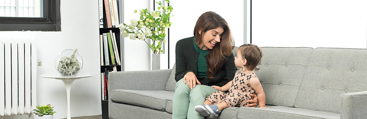 Toddler and mother sitting on a couch while smiling