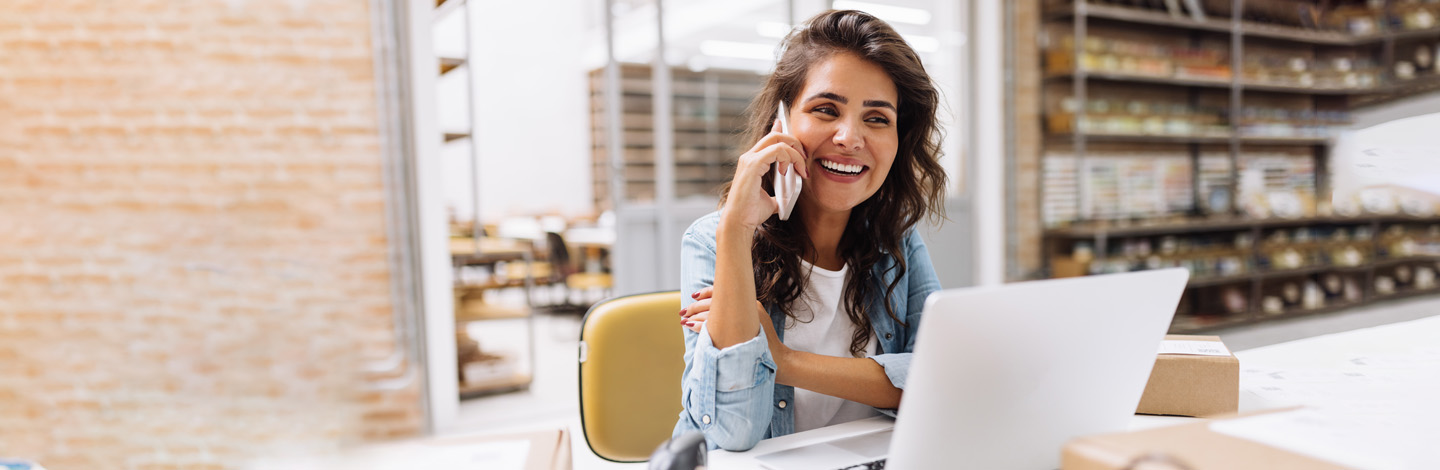 A person talking on a phone while sitting in front of a laptop