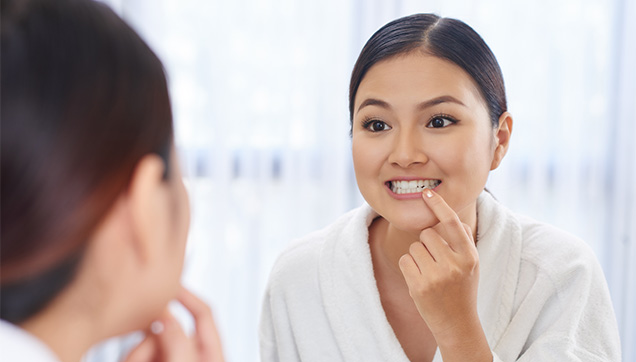 A woman looking at her teeth in the mirror