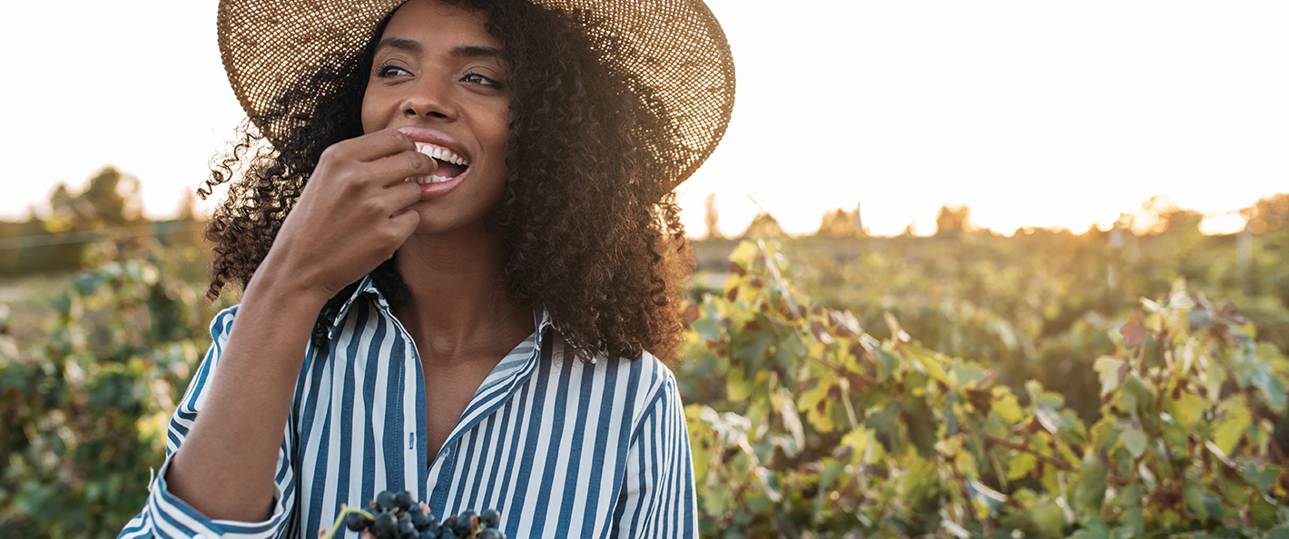 A woman eating grapes in a vineyard