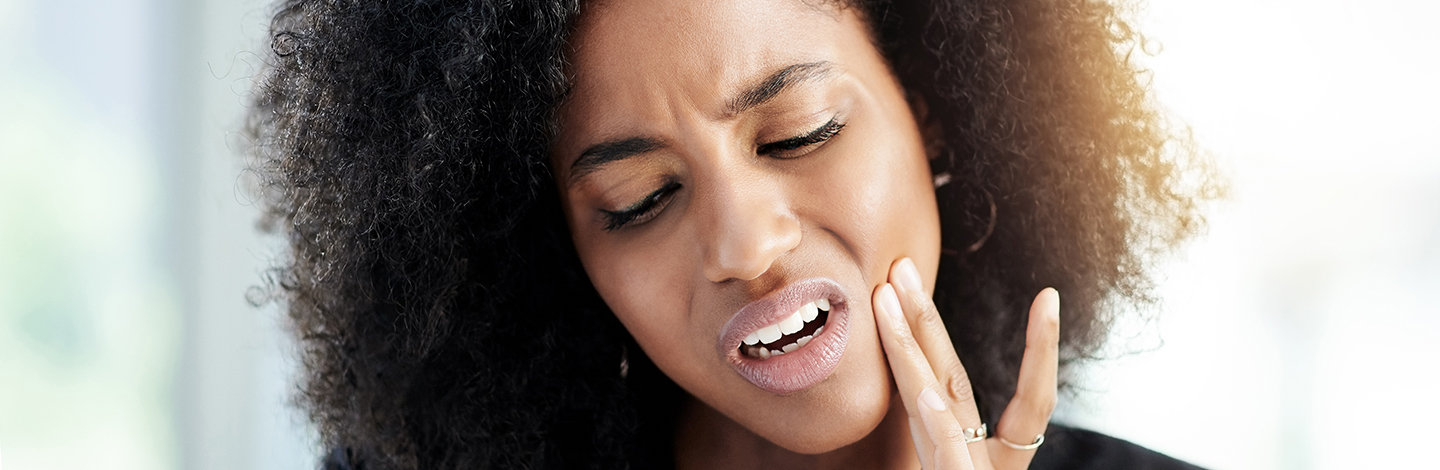 A woman touching her jaw and wincing in pain