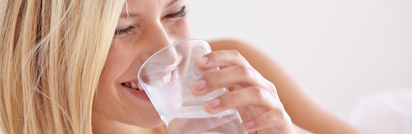 A woman drinking a class of water in bed
