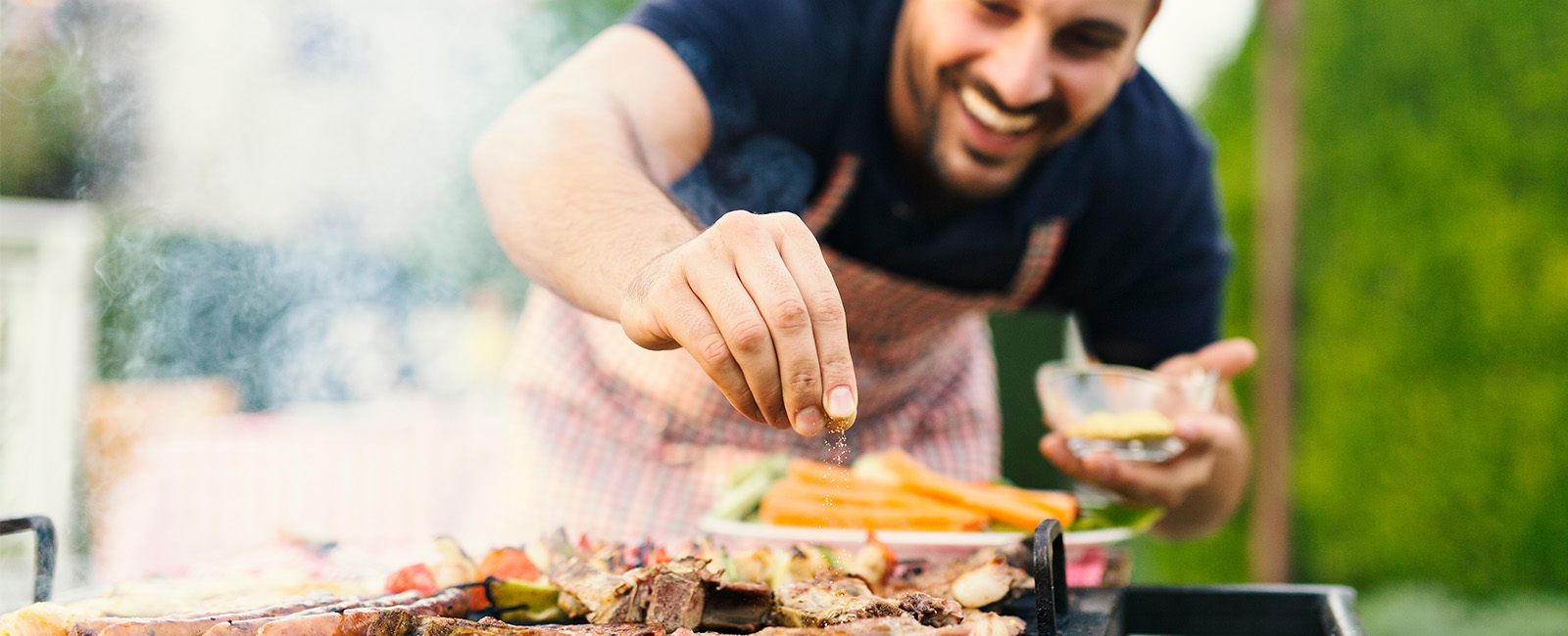 A man seasoning food on a grill