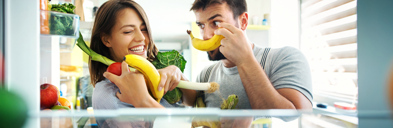 A couple with their hands full of vegetables and fruits
