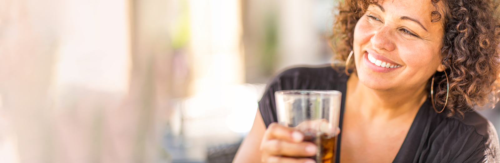 A woman smiling and drinking a soda