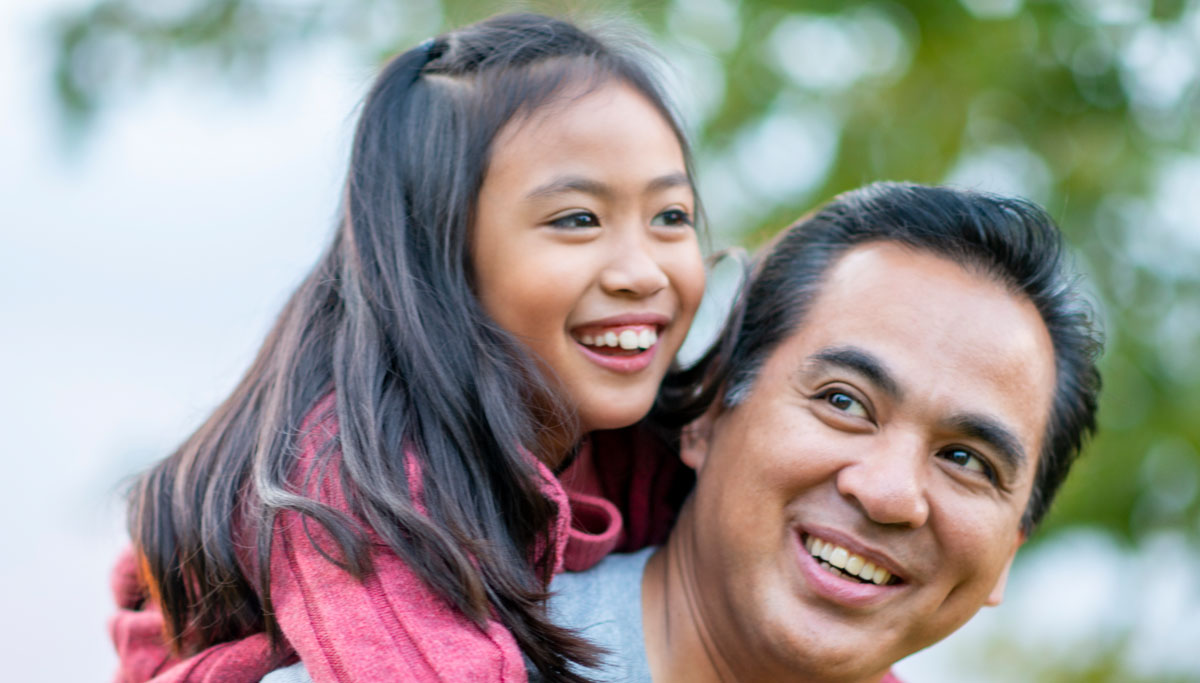 A child hanging onto the back of their father
