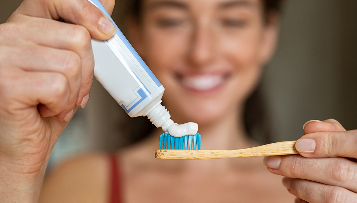 A woman applying toothpaste to a toothbrush
