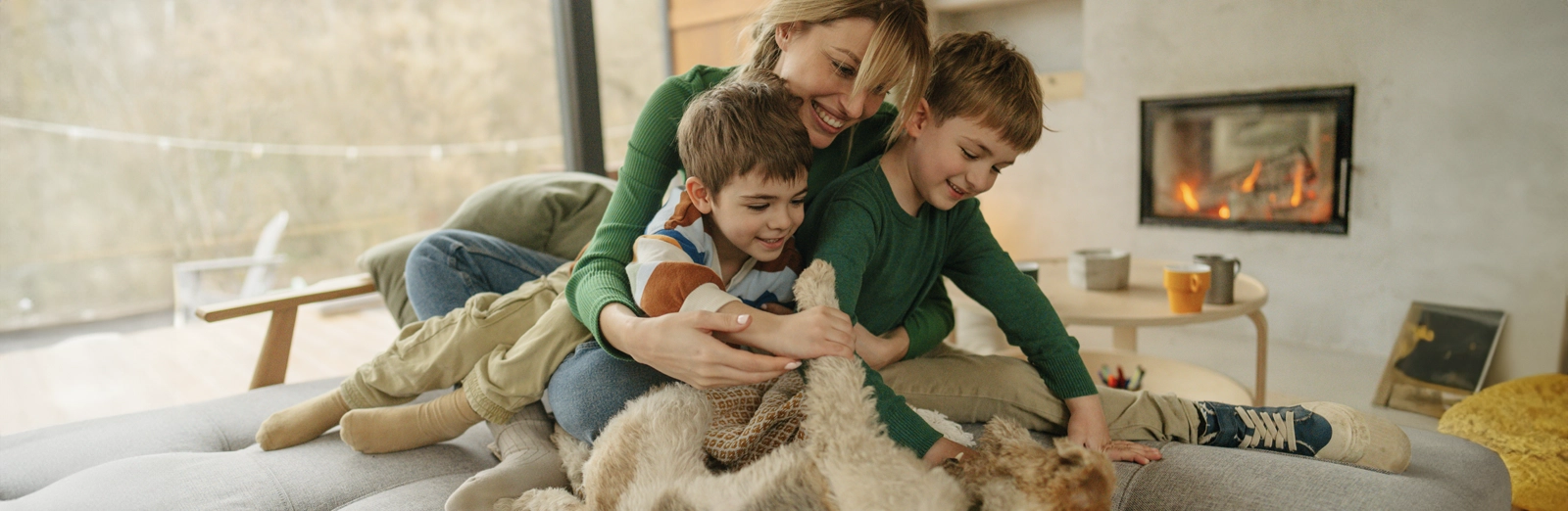 A mother and two children playing with a dog