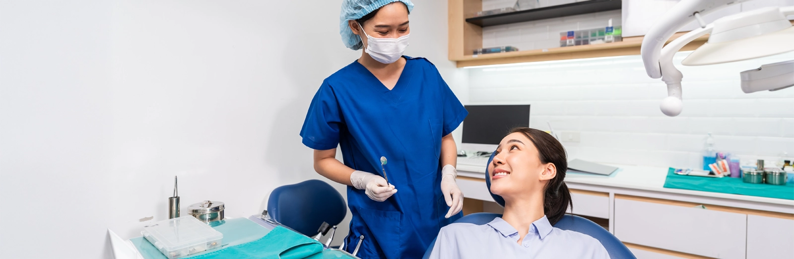 a patient in a dental chair smiling at a dental professional who is preparing for a wisdom teeth removal procedure