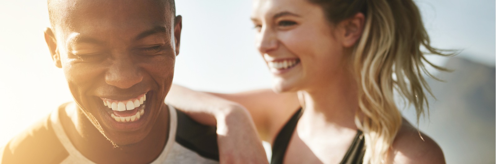 A man and woman laughing outside in the sun