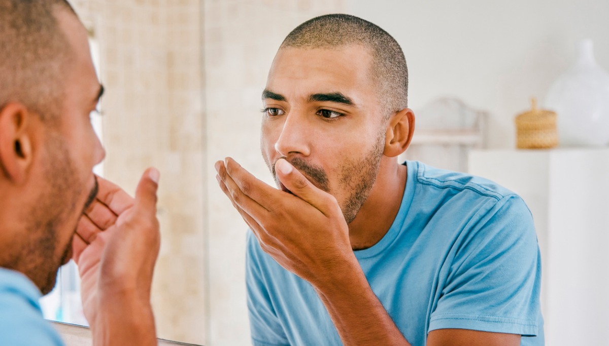 shot-of-a-young-man-smelling-his-breath-during-his-morning-grooming-picture-id1355106336 (1).jpg