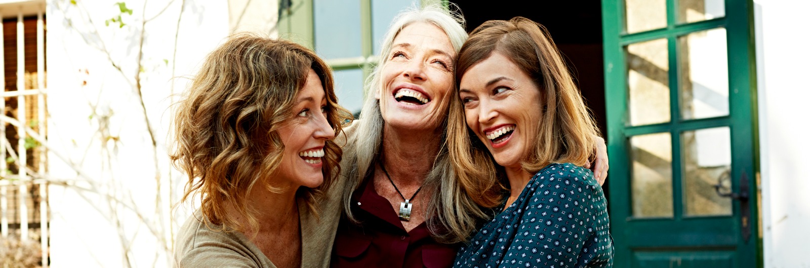 Three women hugging and laughing outside