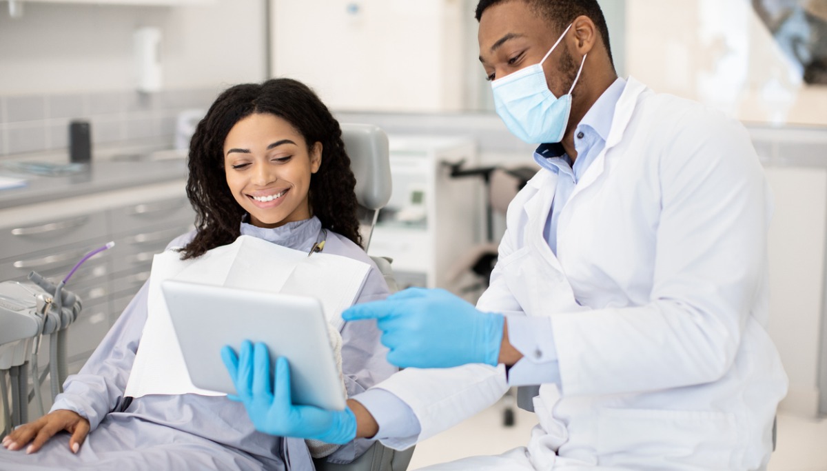 black-dentist-doctor-with-digital-tablet-consulting-female-patient-in-picture-1200x683.jpg