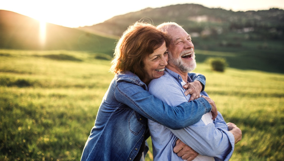 A couple hugging and laughing outside in the sun