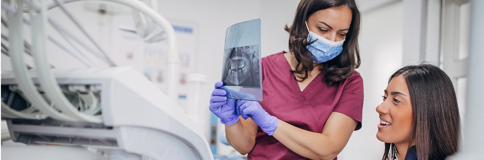 female-dentist-showing-teeth-problem-on-dental-xray-to-patient-in-picture-id1600x529.jpg