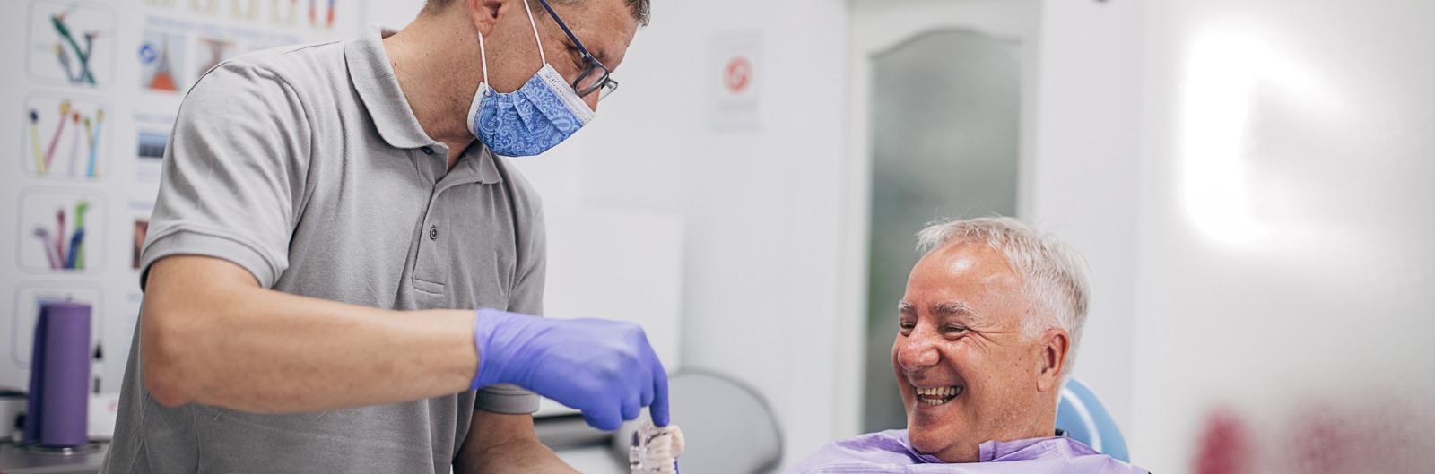 A patient and dentist laughing as they look at a denture