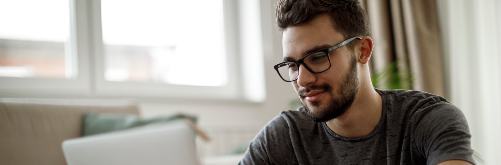 A man with glasses using a laptop.