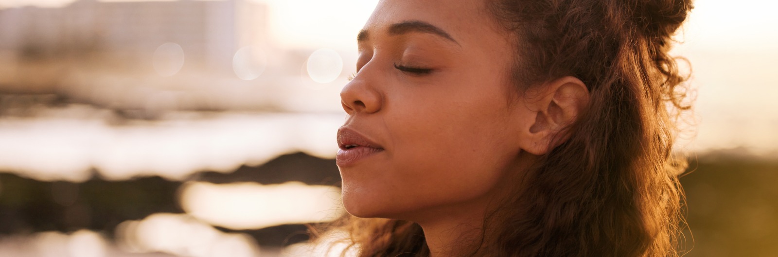A woman breathing deeply outside with her eyes closed