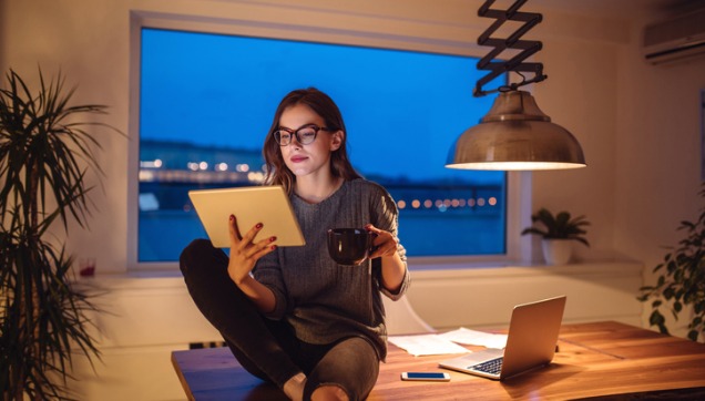 A person drinking coffee and looking at a tablet