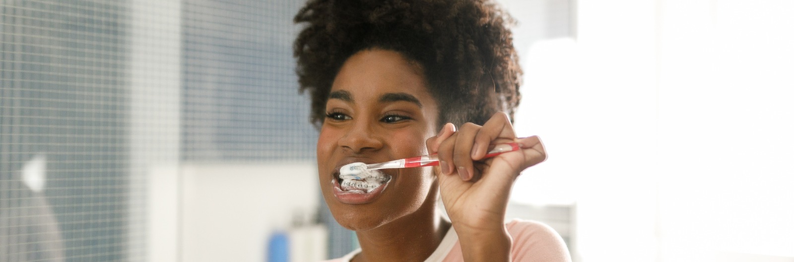 A girl with braces brushes her teeth