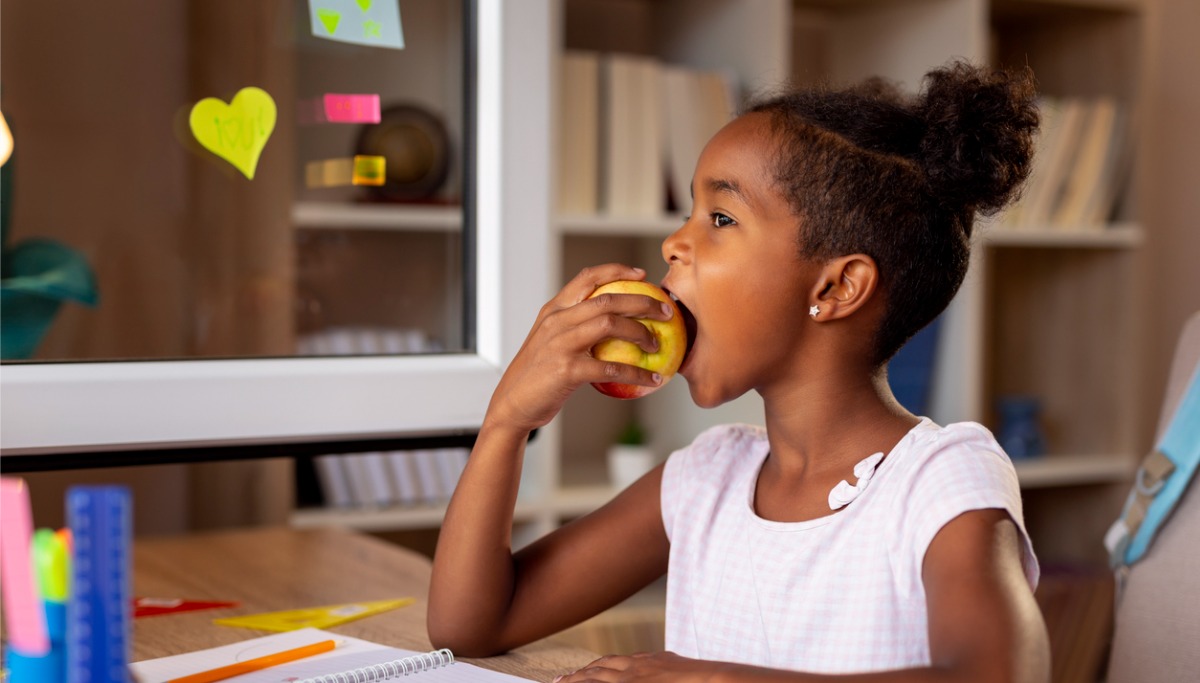 A young child at school eating an apple