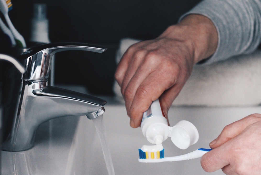 A person applying toothpaste to a toothbrush