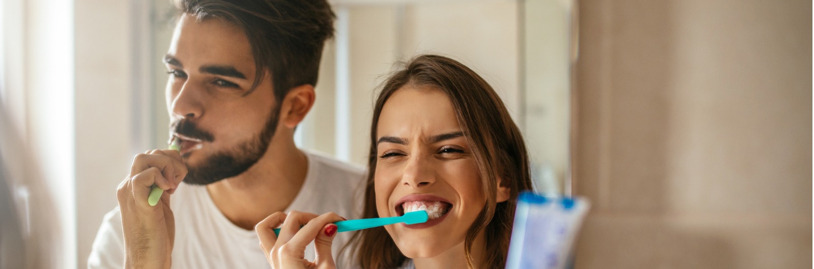 A couple brushing their teeth in a mirror