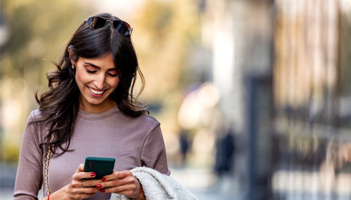 A woman smiling while using using her phone