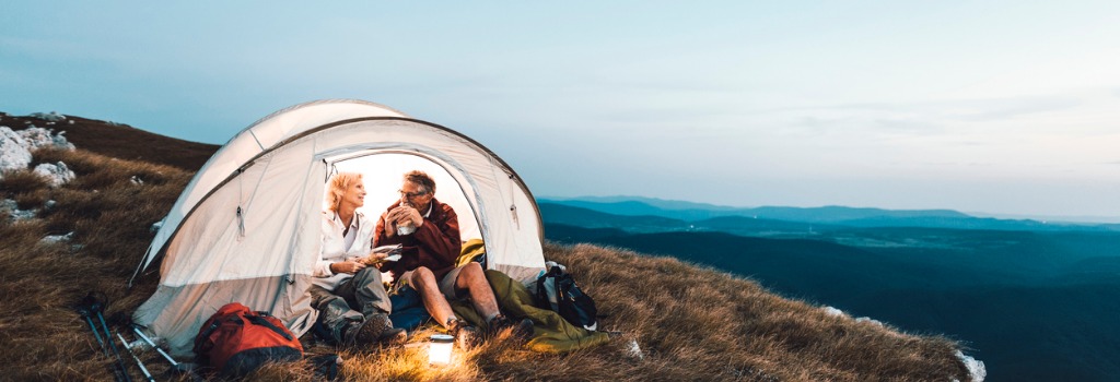 senior-couple-camping-in-the-mountains-and-eating-a-snack-1024x350.jpg