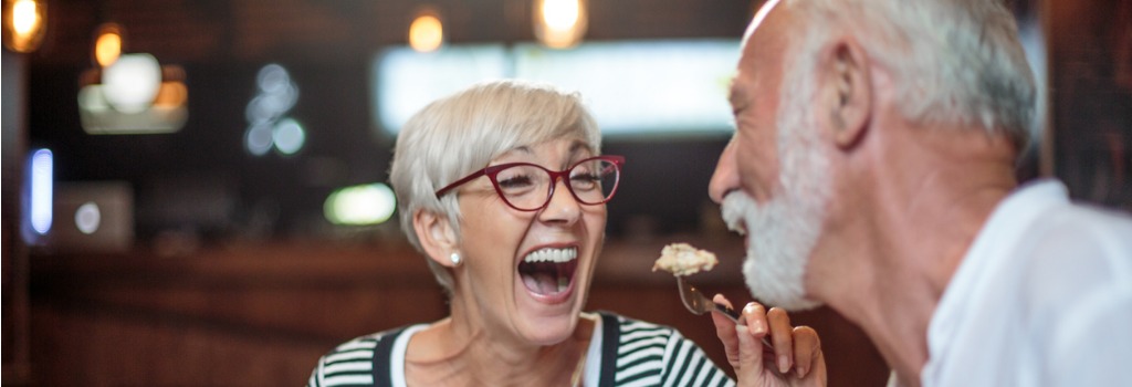 senior-woman-laughing-while-feeding-her-male-partner-in-the-picture-1024x350.jpg