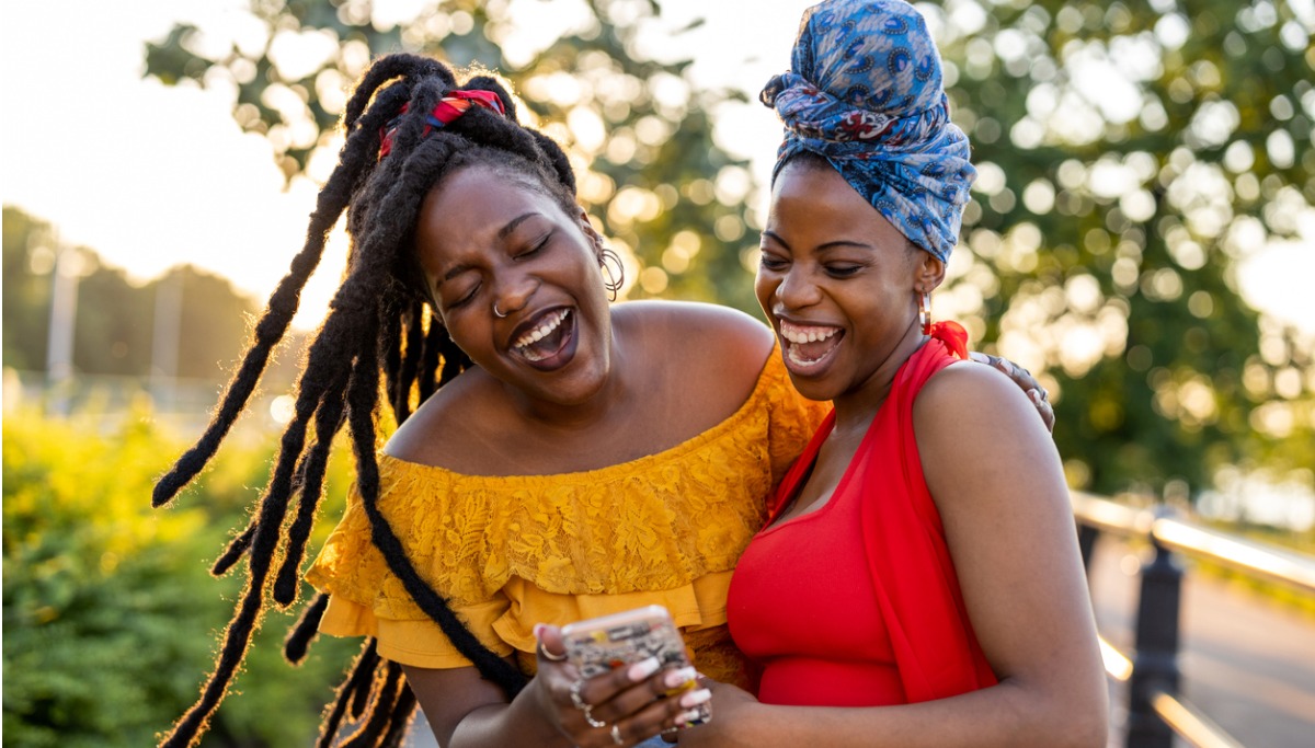 two-female-friends-with-smartphone-smiling-outdoors-picture-1200x683.jpg