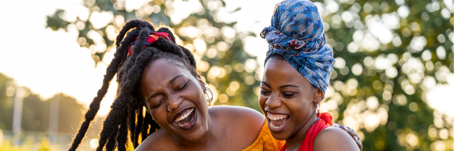Two woman looking at their phone outside and laughing