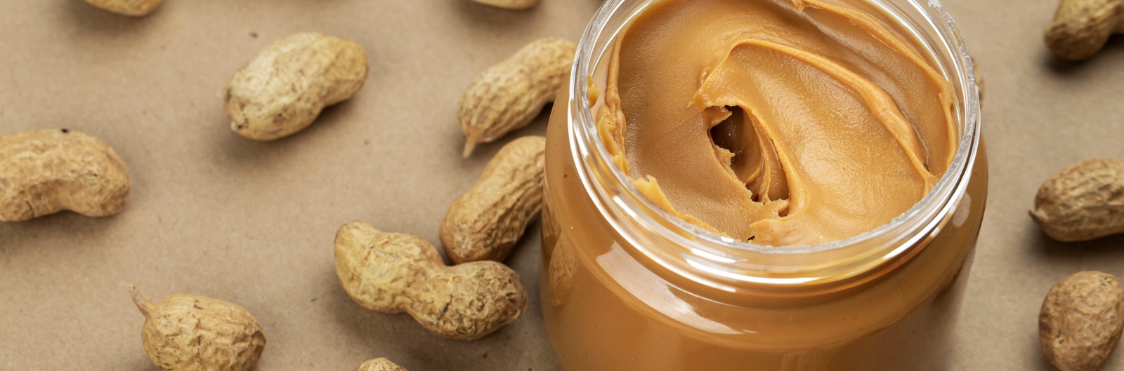 creamy-and-smooth-peanut-butter-in-jar-on-paper-table-picture-1600x529.jpg