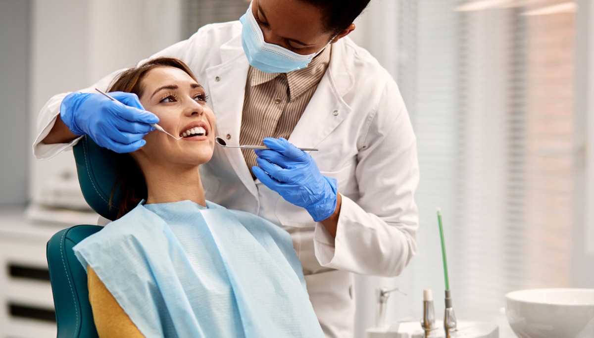 smiling-woman-getting-her-teeth-checked-during-dental-appointment-1200x683.jpg