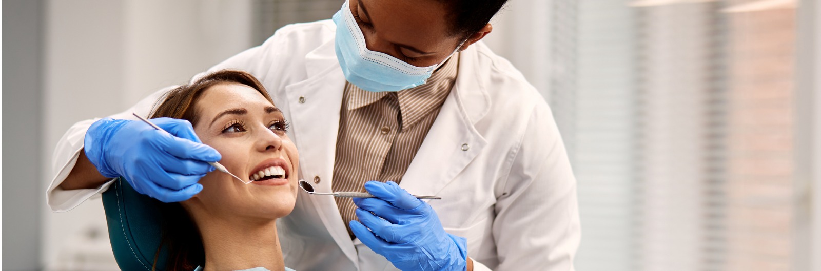 smiling-woman-getting-her-teeth-checked-during-dental-appointment-1600x529.jpg