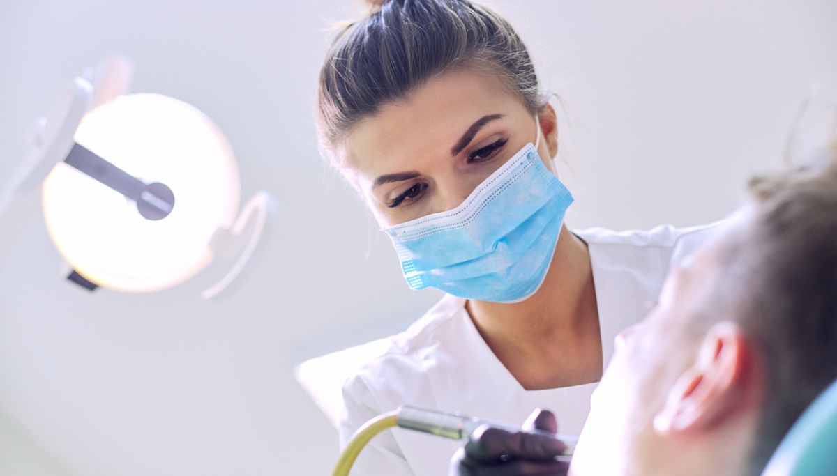 female-dentist-treating-teeth-to-patient-young-man-in-chair-at-dental-picture-1200x683.jpg