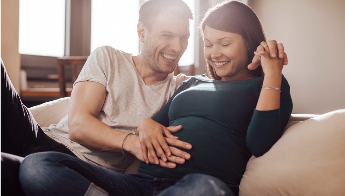 A man with his hand on his pregnant partners belly