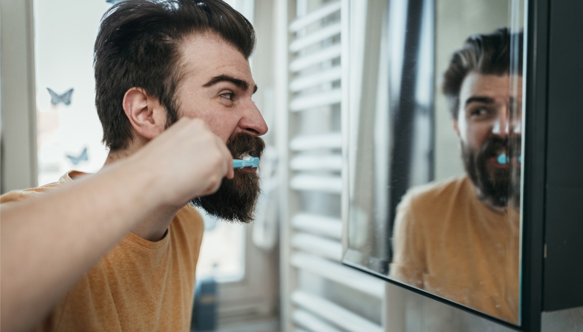 A man with a beard brushing his teeth