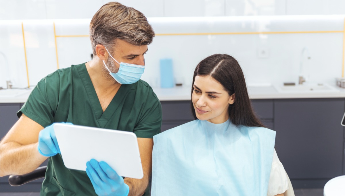 A dentist showing a patient information on a tablet device