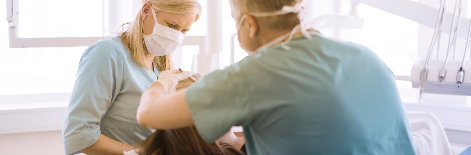 dentist-and-assistant-examining-patient-in-clinic-picture-1600x529.jpg