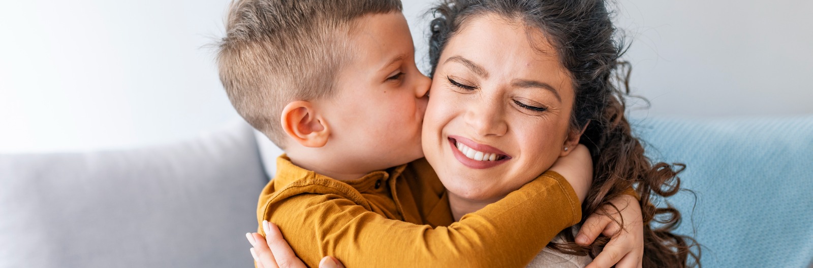 A small child kissing his mother on her cheek