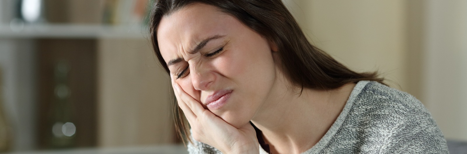 A woman holding the side of her face in pain