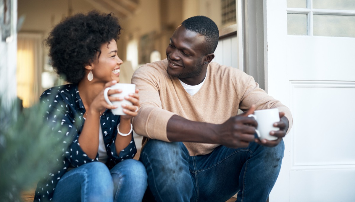 A couple sitting on steps drinking from mugs