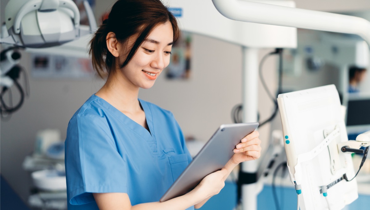 A dentist in an office reading from a tablet device