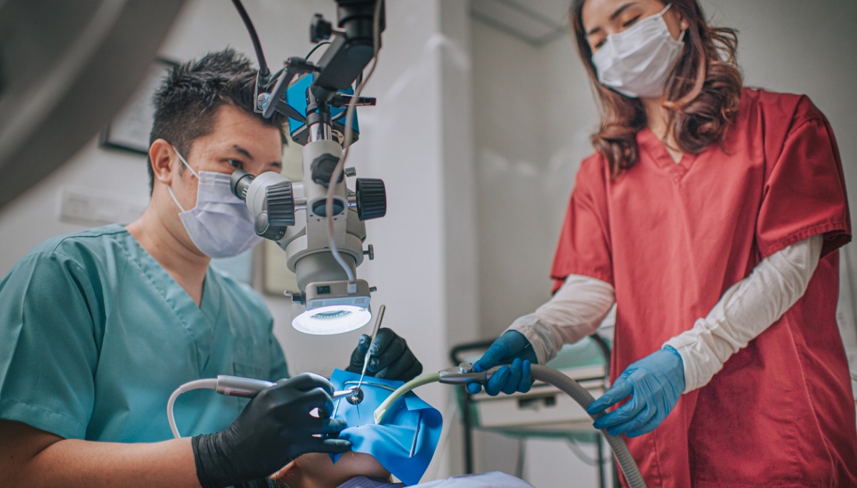 asian-chinese-male-dentist-looking-through-microscope-on-patients-in-picture-1200x683.jpg