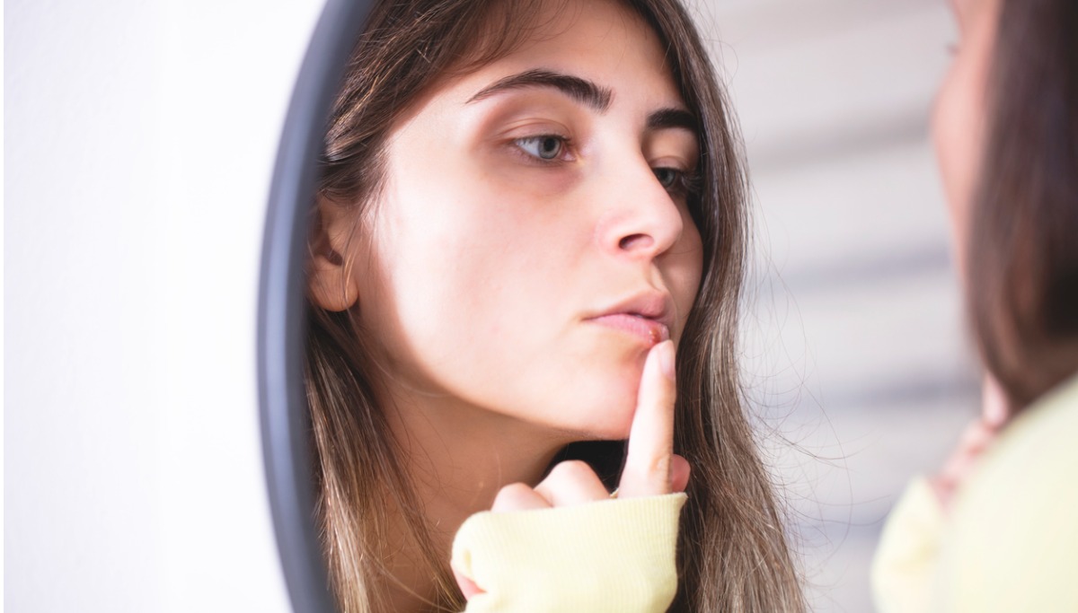 A woman touching a sore on her lip