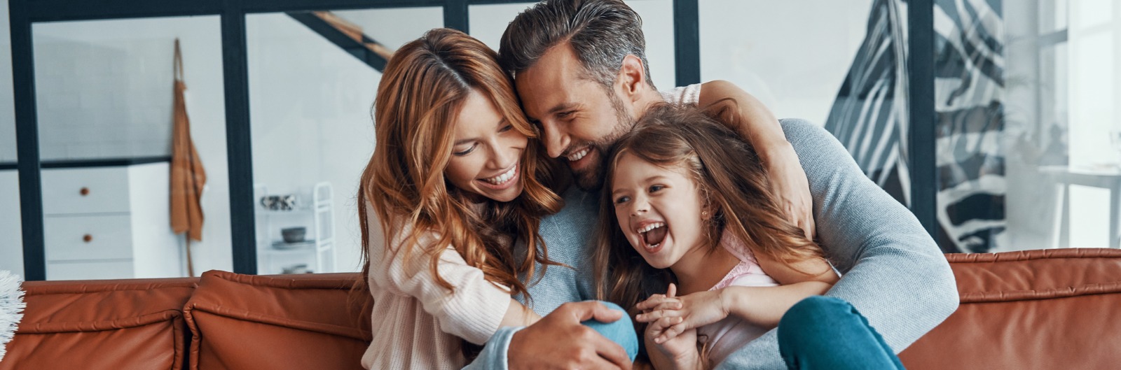 A family laughing and hugging on a coach