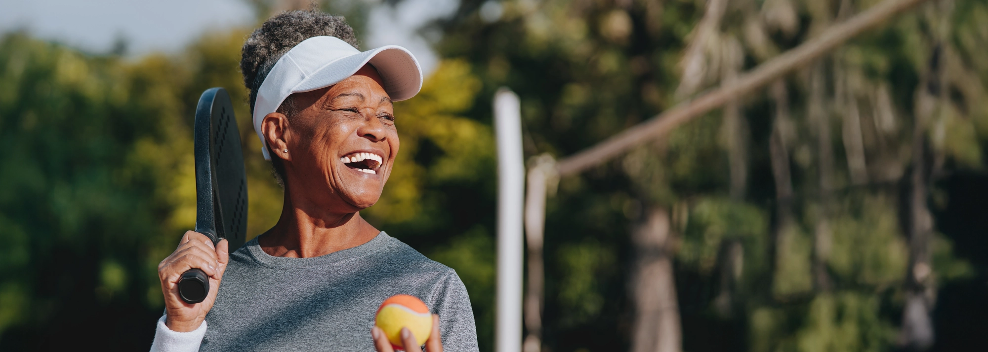 woman-smiling-while-playing-tennis-2000x714.webp