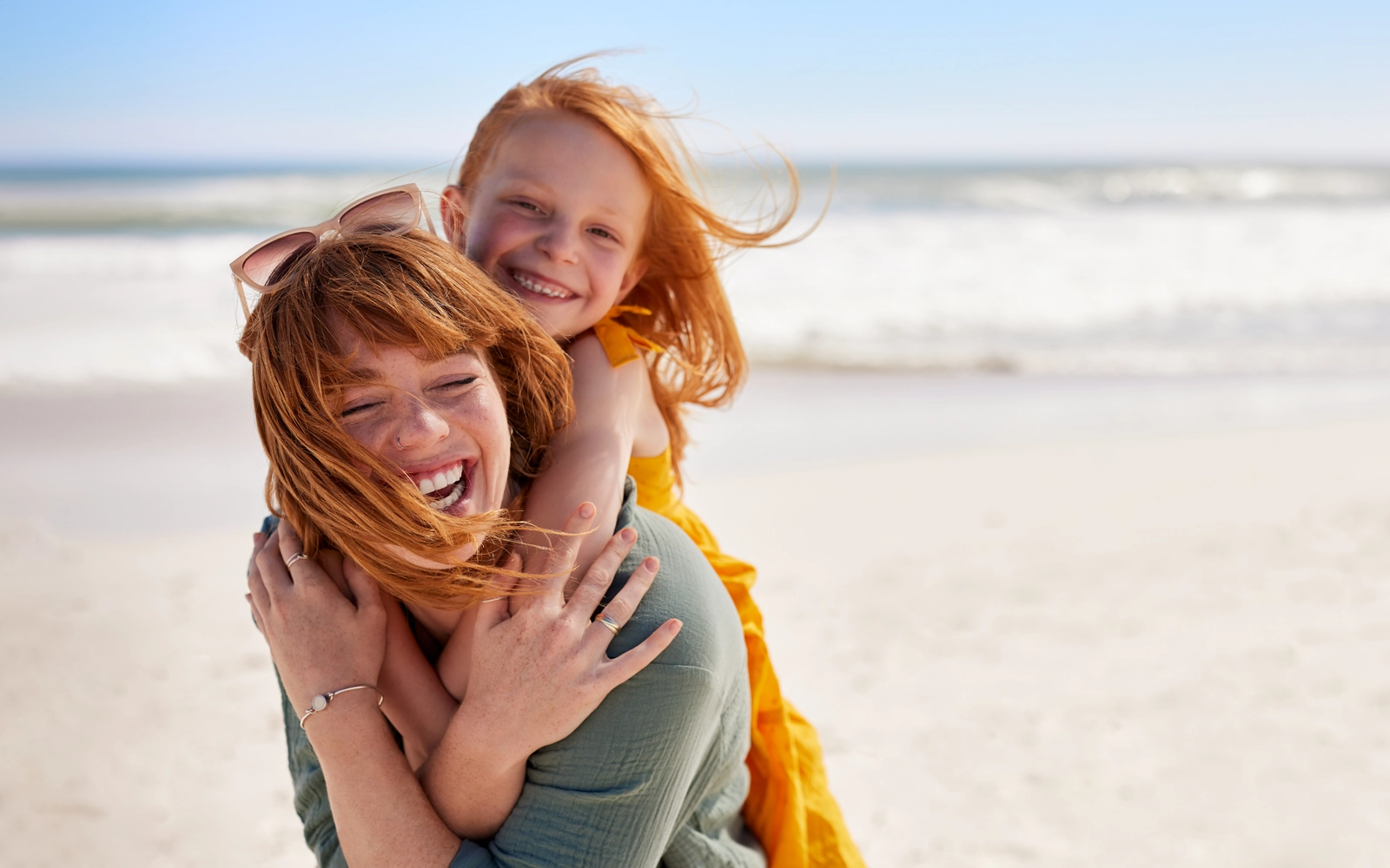 mother_and_child_laughing_at_beach_1600x1000.webp
