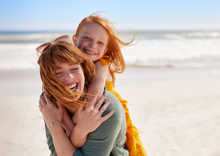 mother_and_child_laughing_at_beach_767x544.webp
